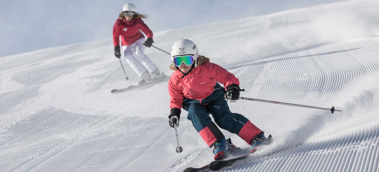 Familie beim Skifahren auf frischer Piste bei Sonnenschein